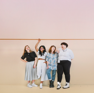 Four girls laughing, standing next to each other wearing vegan Noz sunscreen